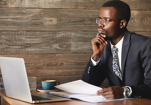 man sitting in thought with his laptop in front of him