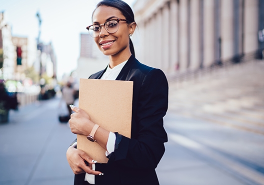 woman standing outside a building holding documents