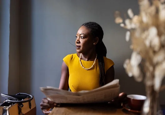 Female sitting at a table with a newspaper in her hand
