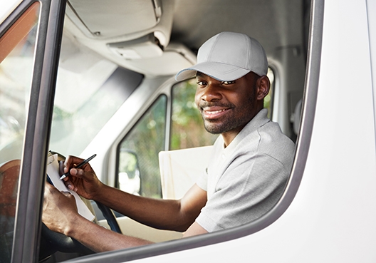 Driver sitting in the driver's seat of truck with his hand on the steering wheel