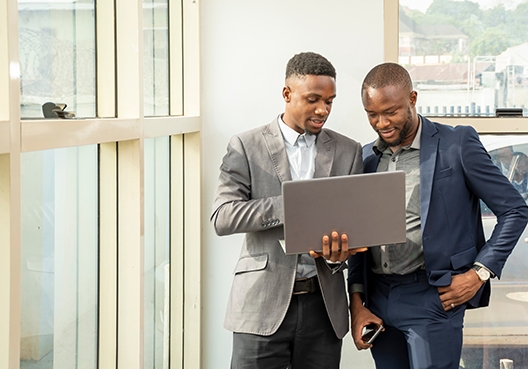 two colleagues standing, looking at a laptop