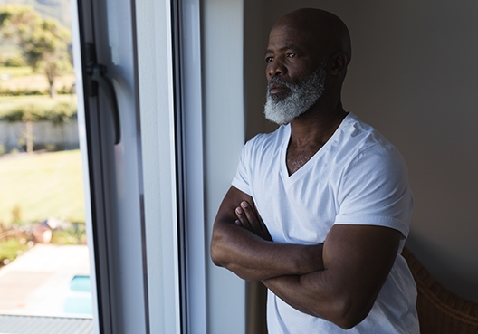 man looking out the window with his arms crossed